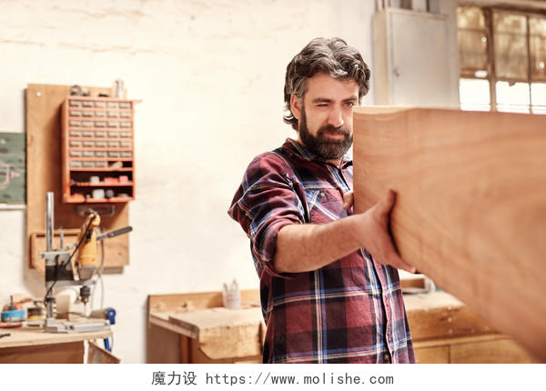 木匠车间里熟练的木工工匠熟练地检查一块木板长度质量